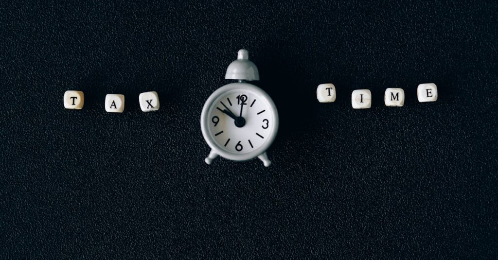 Conceptual image of tax time with clock and letter blocks on black background.